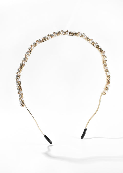 A rhinestone headband in gold frame studded with small clear and pearl beads.