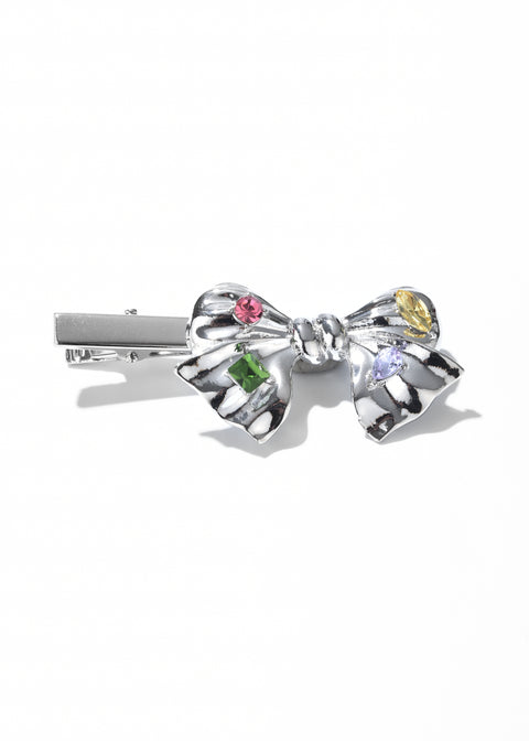 A bow clip decorated with a colorful array of green and pink gemstones.