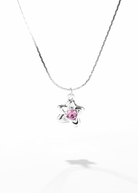 A necklace with a star pendant that has a pink gemstone set in the center.