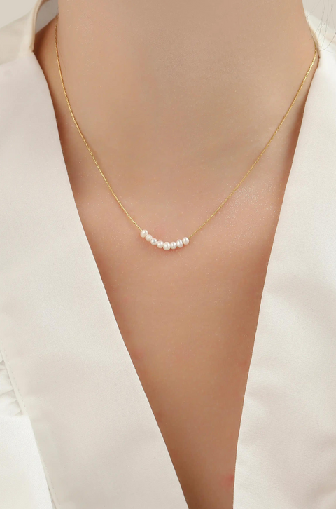 A dainty pearl necklace with chain and shiny pearls lined up in the center.