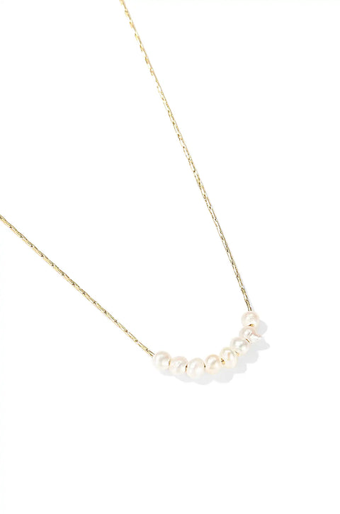 A dainty pearl necklace with chain and shiny pearls lined up in the center.