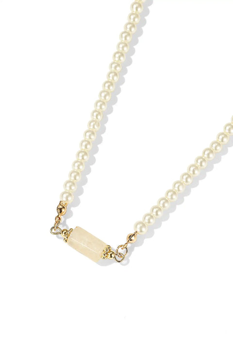 This natural stone necklace features a string of shiny pearls with a soft stone in the center.