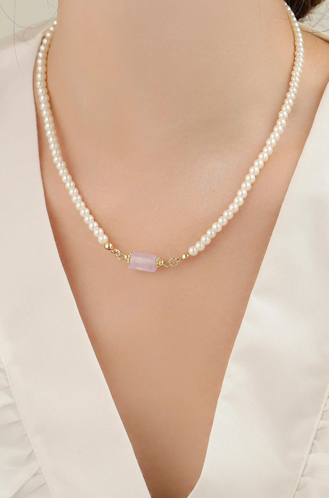 This pearl with pendant necklace features a string of shiny pearls with a soft stone in the center.