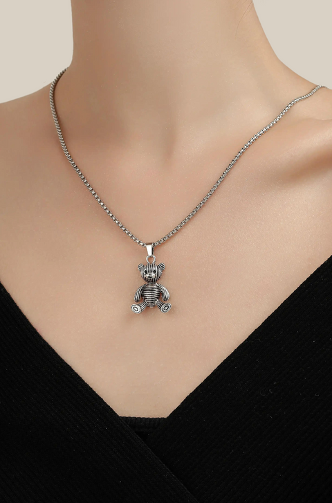 A silver teddy bear necklace with a striped texture, hanging from a sturdy link chain.