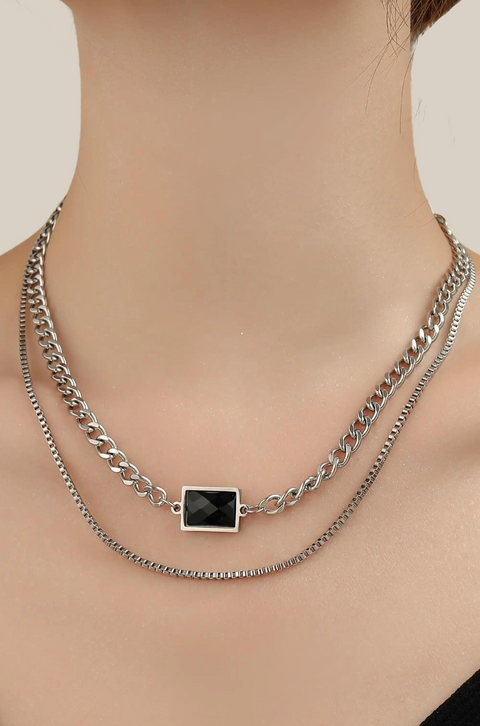 An onyx stone necklace with a black square gem centered on a layered silver chain.