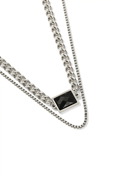 An onyx stone necklace with a black square gem centered on a layered silver chain.
