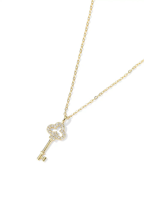 A gold key necklace with a heart-shaped top encrusted with small diamonds.
