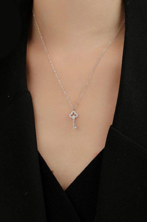 A gold key necklace with a heart-shaped top encrusted with small diamonds.