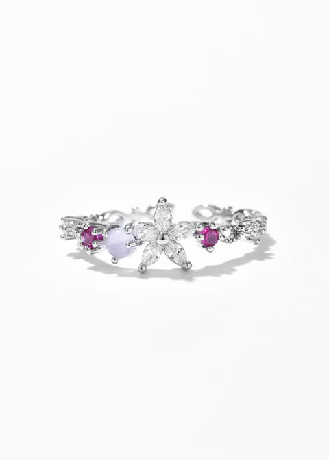 Floral ring with flower petal design and small gemstones on each side.