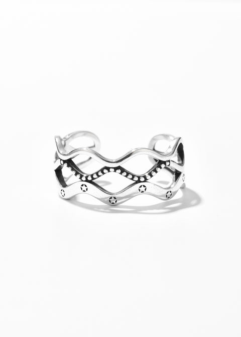 A wave ring with open design featuring dotted details and small, etched stars on the band.