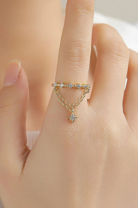 A gold celestial ring featuring a chain and a star charm.