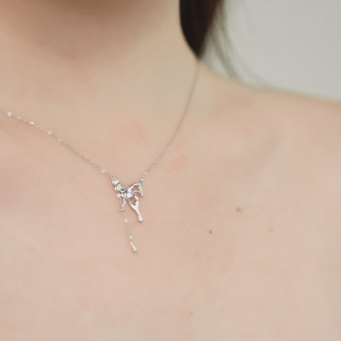 A butterfly necklace that has a small, purple gemstone at its center, all hanging on a sterling silver pendant necklace.