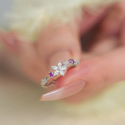 Floral ring with flower petal design and small gemstones on each side.
