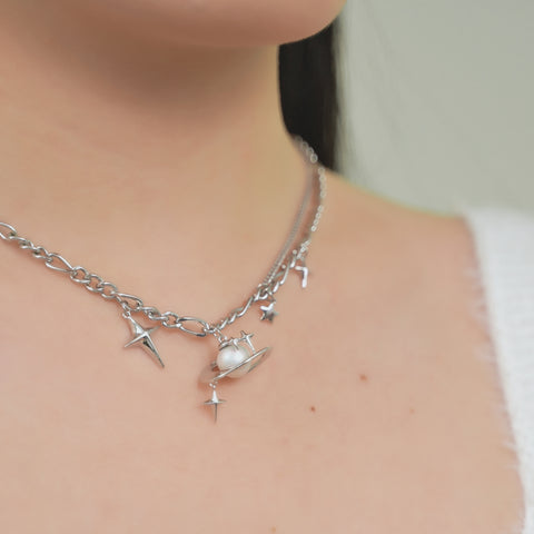A gold plated chain with pearl pendant necklace, consists of a couple of stars, and a pearl in the middle as if it is a planet with rings.