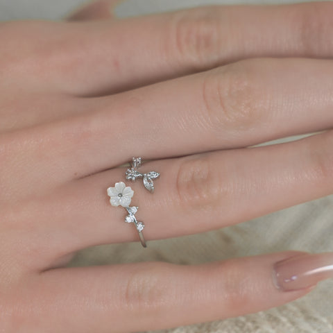 A silver open ring featuring a floral ring design, complemented by small crystal details along the petals and band.