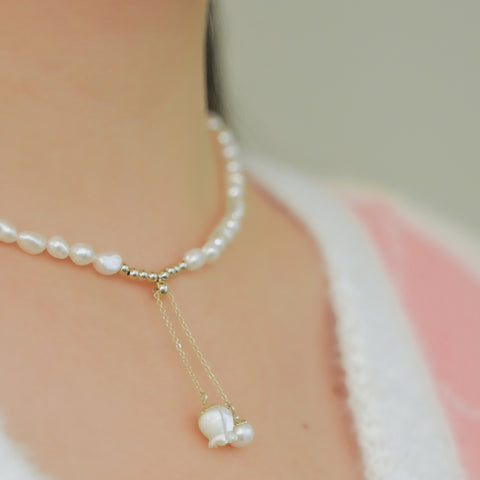 Freshwater pearl necklace forming a chain and a small flower pendant hanging from a gold chain.