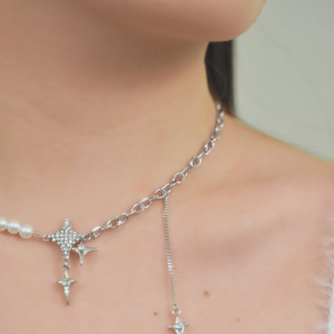 A constellation necklace with star pendant a strand of pearls, creating a lariat style.
