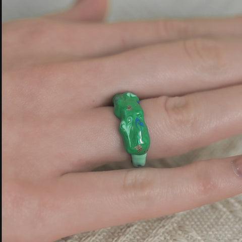 A wavy-shaped unique ring with a glossy finish, a statement ring accented by swirls and gold embellishments.