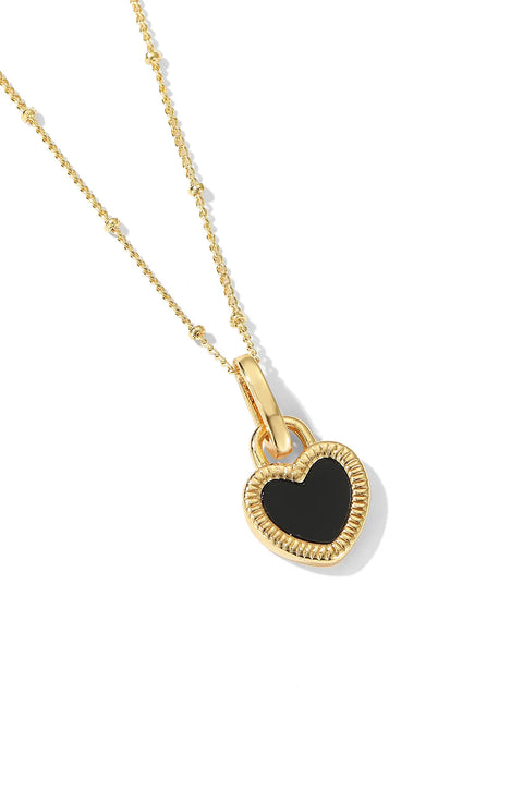 A black heart necklace with a heart pendant surrounded by a textured gold frame.