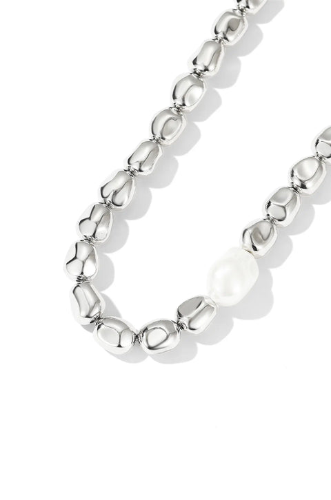 A silver beaded necklace featuring shiny, smooth beads with a single, larger asymmetrical pearl.