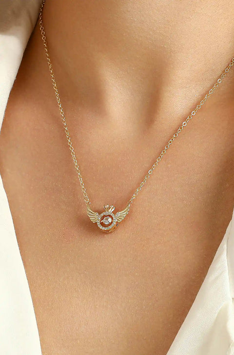 An angel wing necklace featuring central, sparkling gem surrounded by smaller crystals.