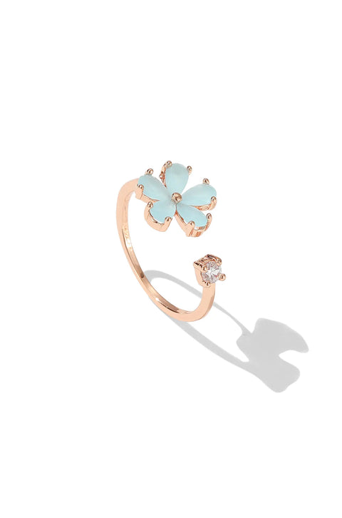 Dainty gold ring featuring gemstone flower, with a small clear stone on the opposite end.