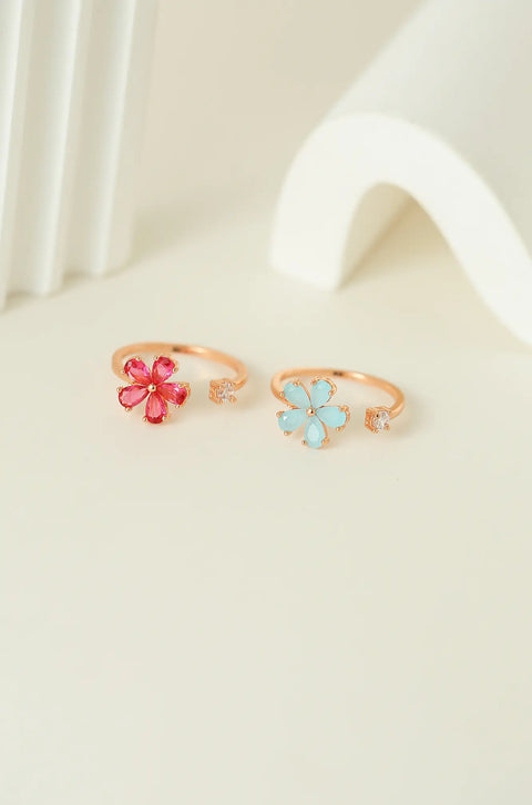 Dainty gold ring featuring gemstone flower, with a small clear stone on the opposite end.