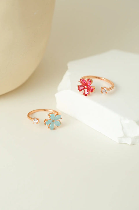 Dainty gold ring featuring gemstone flower, with a small clear stone on the opposite end.