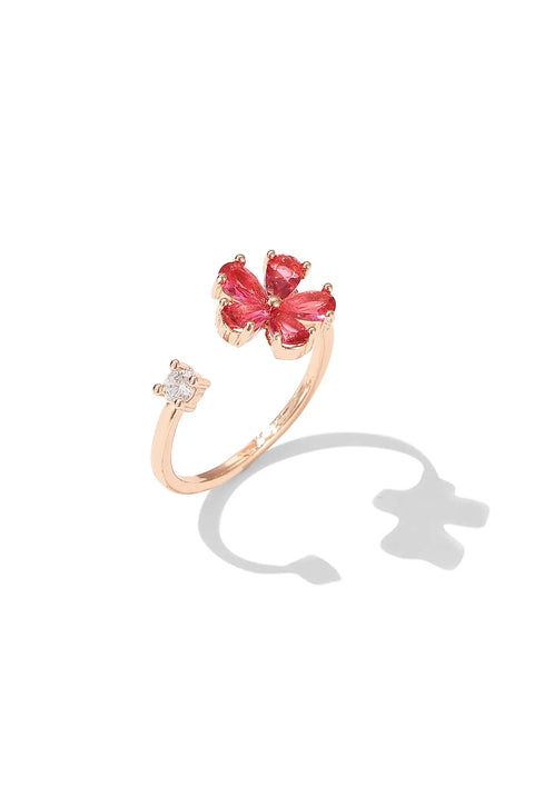 Dainty gold ring featuring gemstone flower, with a small clear stone on the opposite end.
