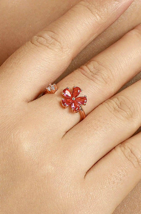 Dainty gold ring featuring gemstone flower, with a small clear stone on the opposite end.