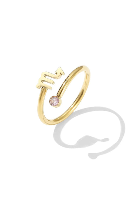 A gold Scorpio ring with a small pink gemstone at one end and the zodiac symbol at the other.
