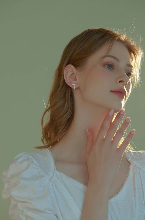 Teardrop crystal earrings dangling from bar with small stones.