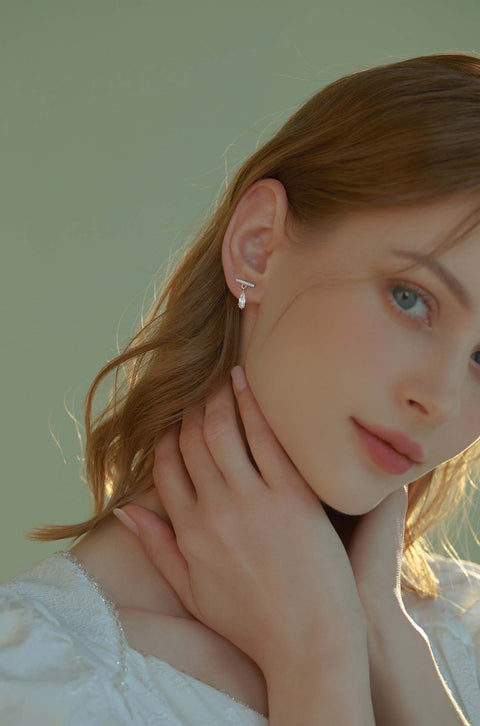 Teardrop crystal earrings dangling from bar with small stones.
