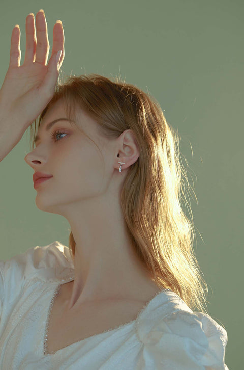 Teardrop crystal earrings dangling from bar with small stones.