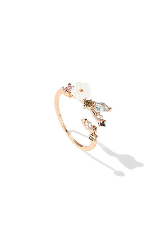 An open-ended floral ring, accented by a cluster of multicolored gemstones, set on a band of rose gold ring.