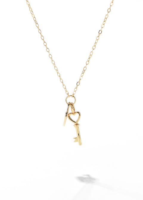 A key and lock pendant necklace with two golden keys, one shaped like a heart.