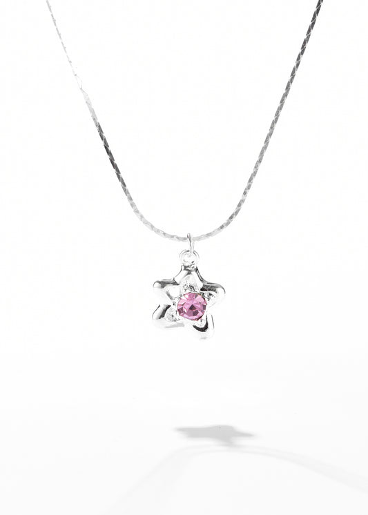 A necklace with a star pendant that has a pink gemstone set in the center.