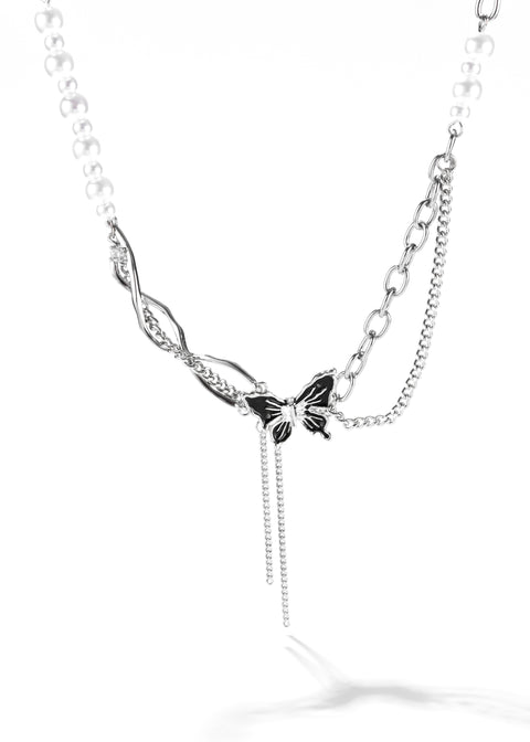 A lariat necklace that combines a string of pearls with a silver chain and a butterfly pendant.
