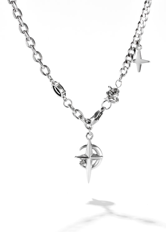 A star and moon pendant with a silver chain necklace. The star is overlaid on a crescent moon, both with pointed tips and a small, shiny stone set into the star part.