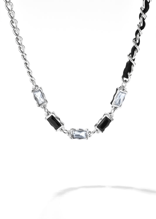 A gem leather necklace with a chain, interspersed with clear and black gemstones.