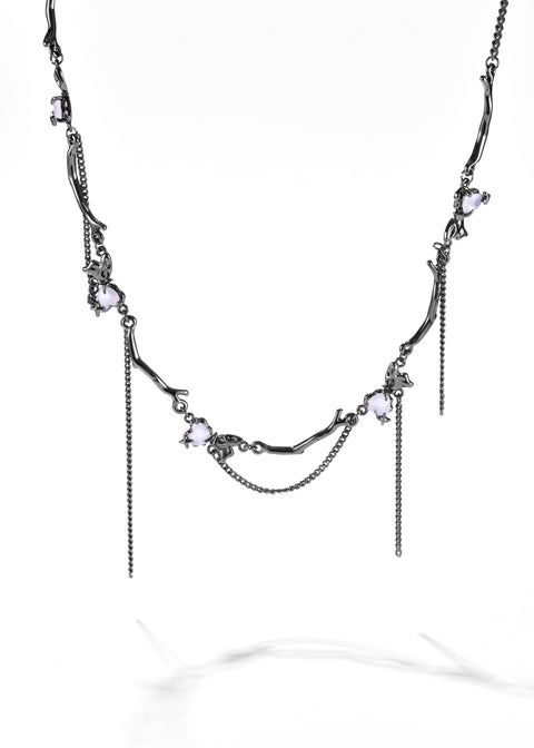Bow necklace with gunmetal chain links, small bow motifs and pale pink gemstones.