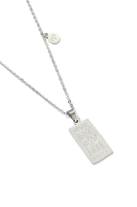 An Aries necklace featuring rectangular pendant with floral design, and a smaller, round charm with the zodiac sign.