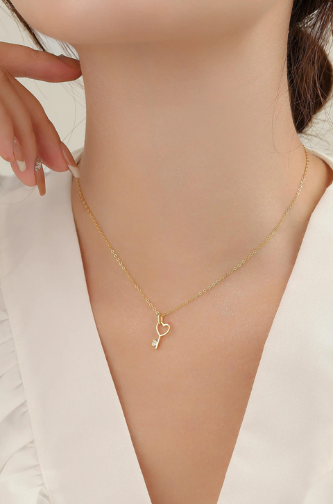 A heart key necklace in a golden chain.