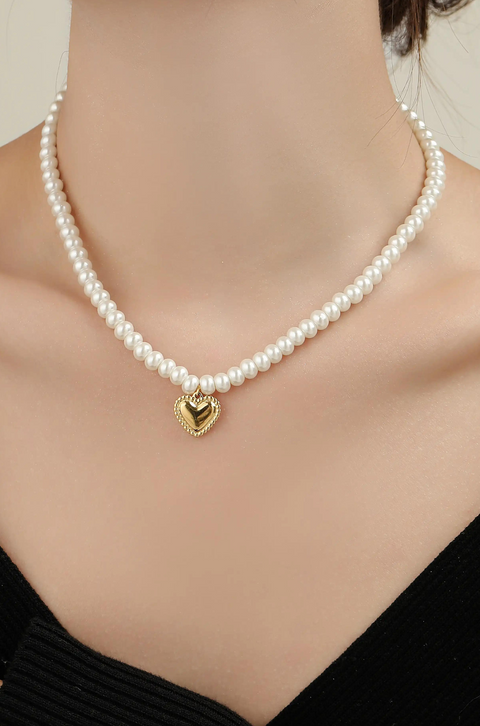 A heart pearl necklace with shiny pearls and a gold heart pendant.