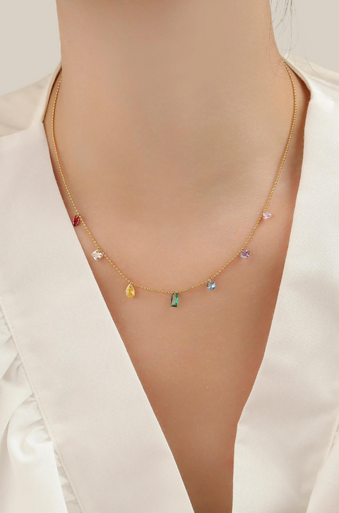 A rainbow gem necklace with various colorful gemstones on a gold chain.