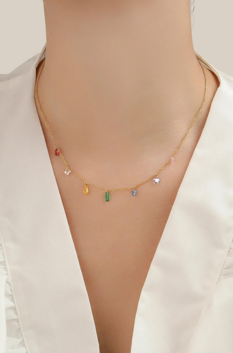 A rainbow gem necklace with various colorful gemstones on a gold chain.