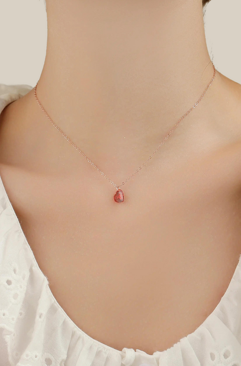 A red heart necklace with sparkling pendant on a chain.