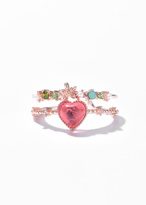 Floral ring with a heart-shaped stone at the center and smaller floral and gemstone embellishments along the band.