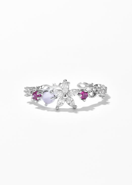 An open ring with a flower petal design and small gemstones on each side.