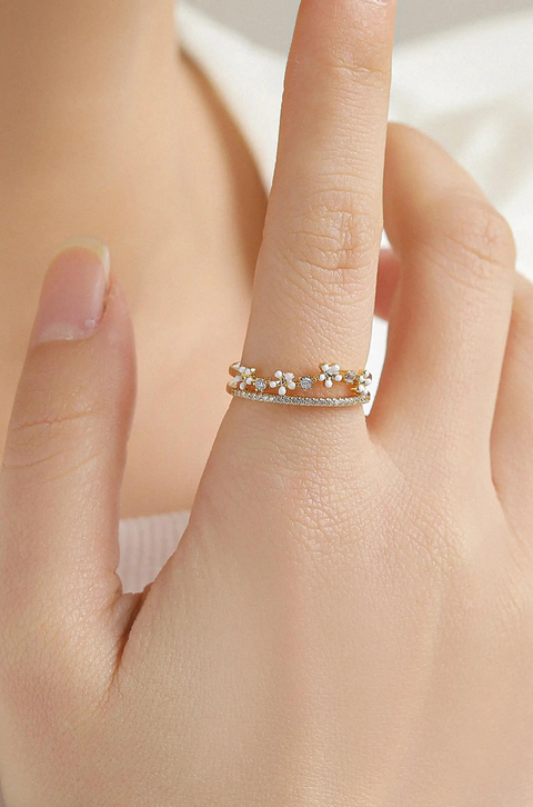 A flower gold ring with open design featuring small floral accents and sparkling stones.